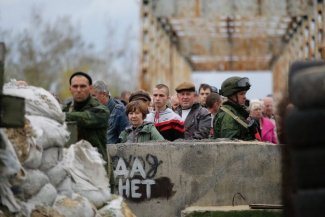 In the picture local ukrainian people and two soldiers on military post on the bridge
