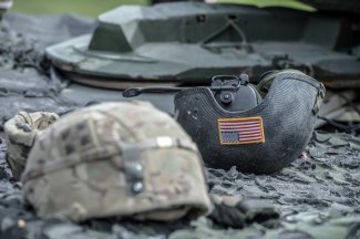 Two soldier helmets, infantry helmet in the foreground, tanker helmet inverted by 180 with the US flag visible in the second.