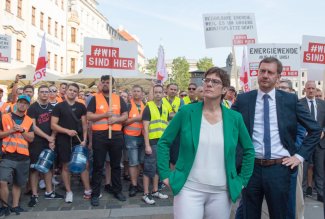 Annegret Kramp-Karrenbauer i Michael Kretschmer, na drugim planie protestujący związkowcy