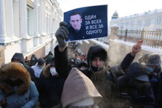 Zdjęcie protestującego trzymającego w ręku banner z napisem "Jeden za wszystkich, wszyscy za jednego".