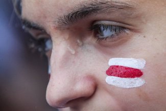 Zdjęcie przedstawia kobietę z namalowaną na twarzy flagą biało-czerwono-białą