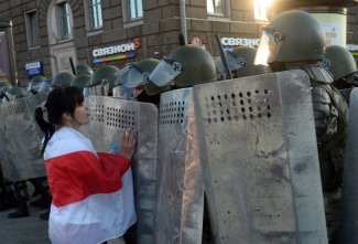 Zdjęcie przedstawia osobę protestującą i funkcjonariuszy
