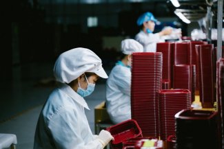 The photo shows a person working in a mask, probably in a factory 